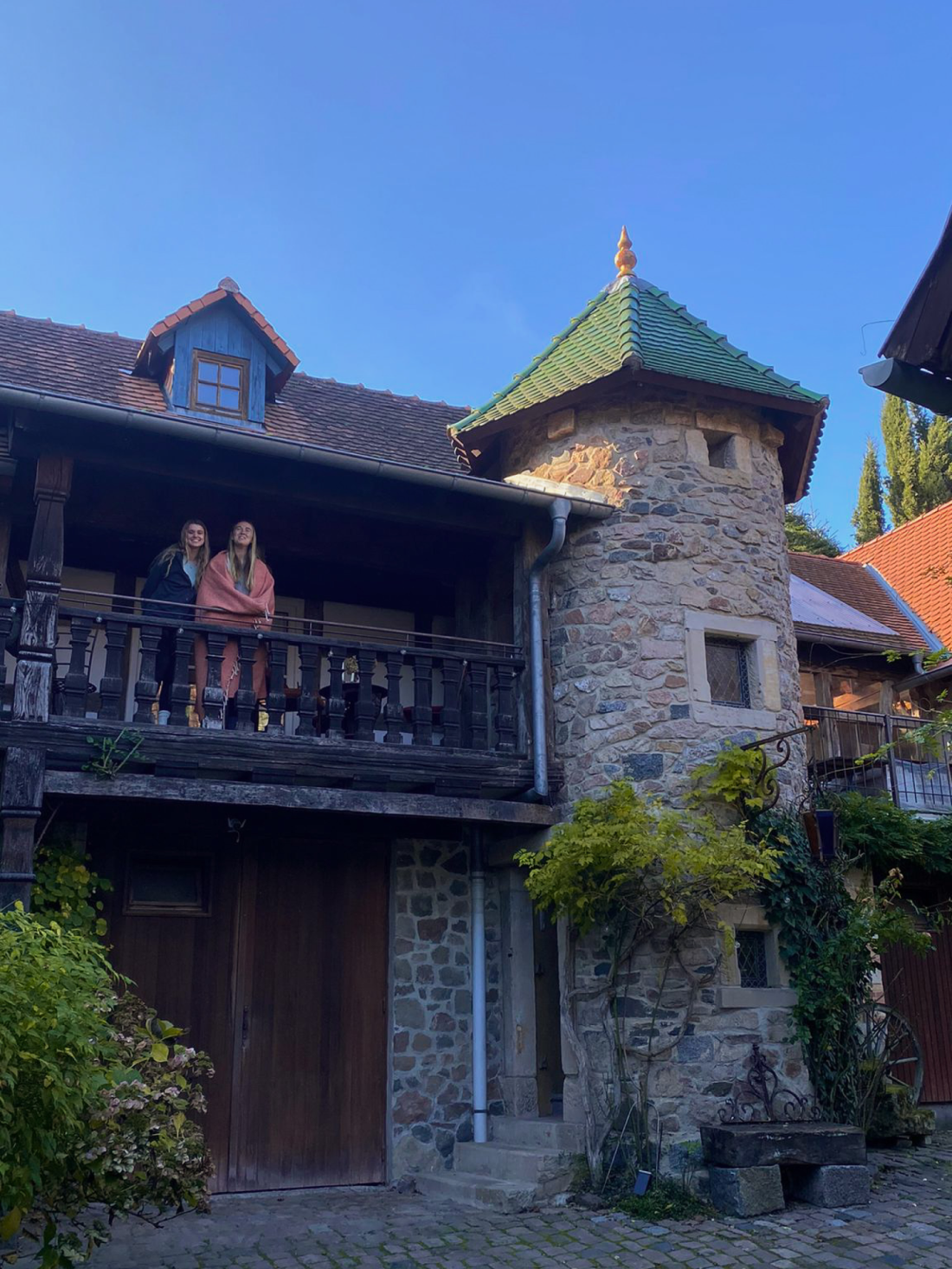 Two women on a balcony of a stone building